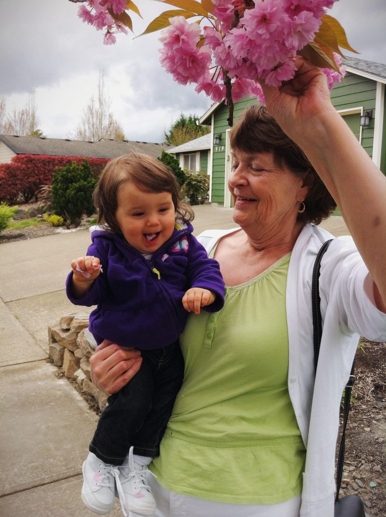 Granny holding my daughter as a baby up to a flowering tree for some hands on exploration on a cloudy day.